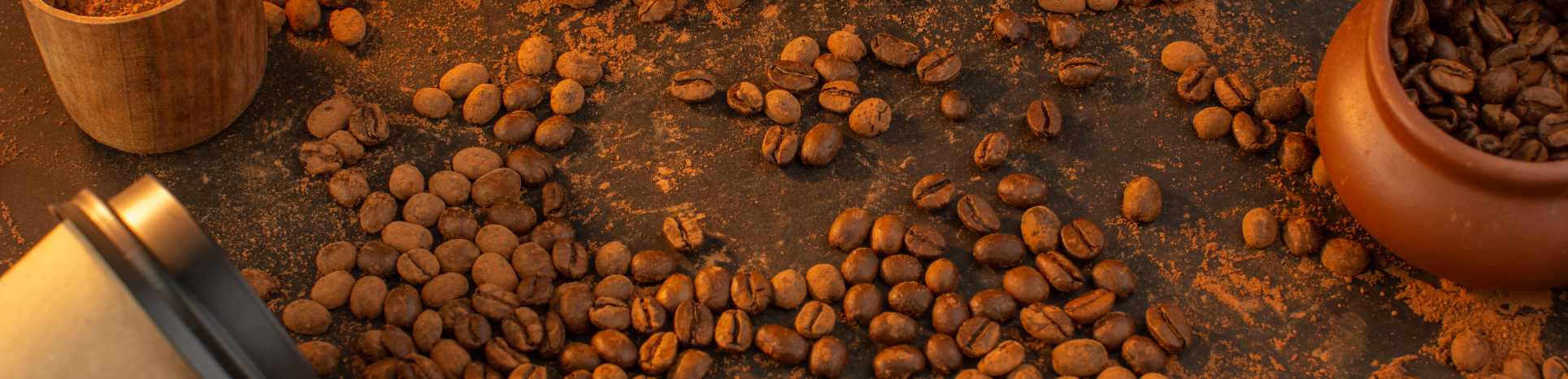 Muitos grãos de café espalhados no chão, um jarro com grãos ao lado e um copo de café marrom claro de tampa preta no campo inferior direito